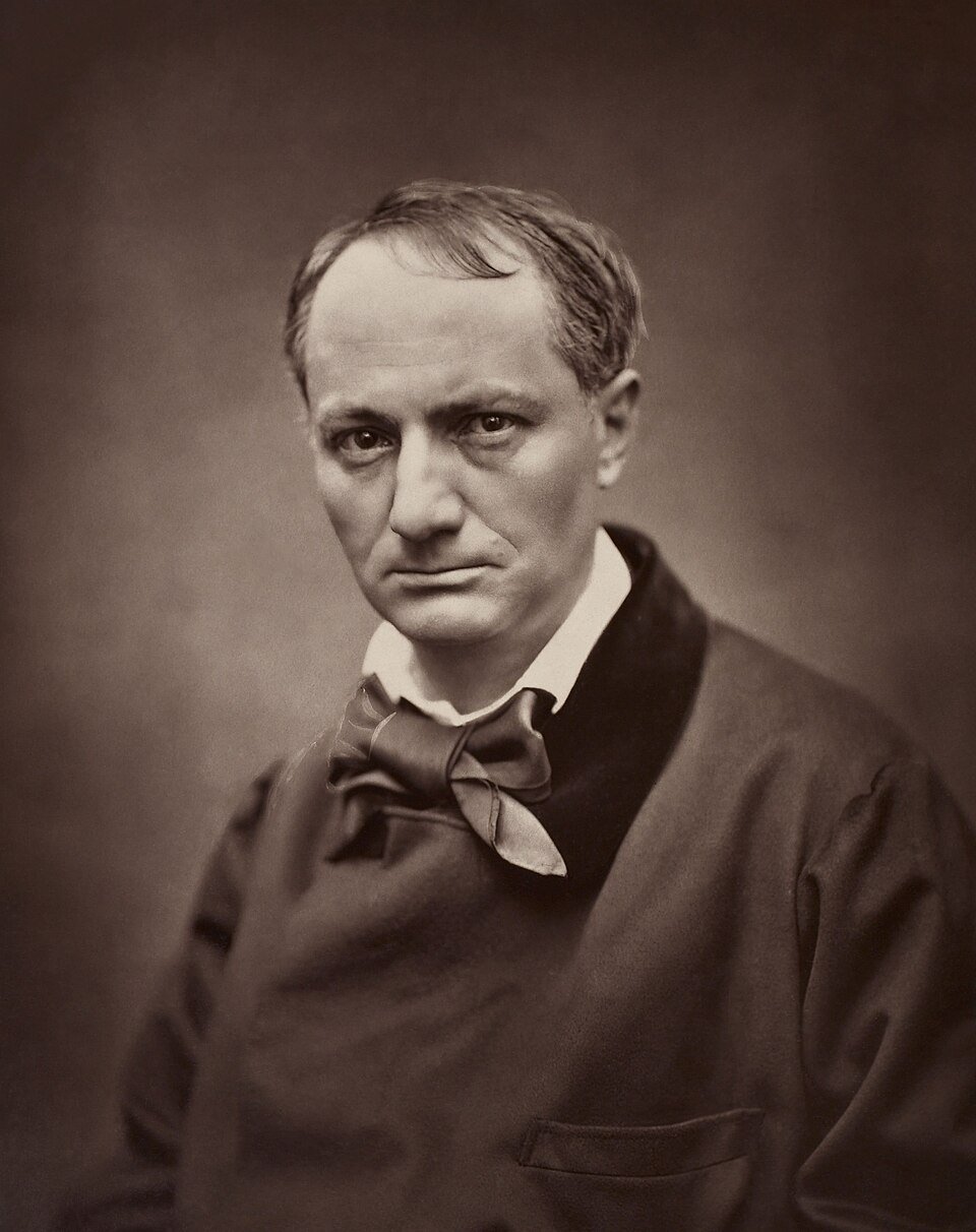 Photographie sépia d'un homme au front dégarni, au regard sombre et dur, portant un large nœud de cravate