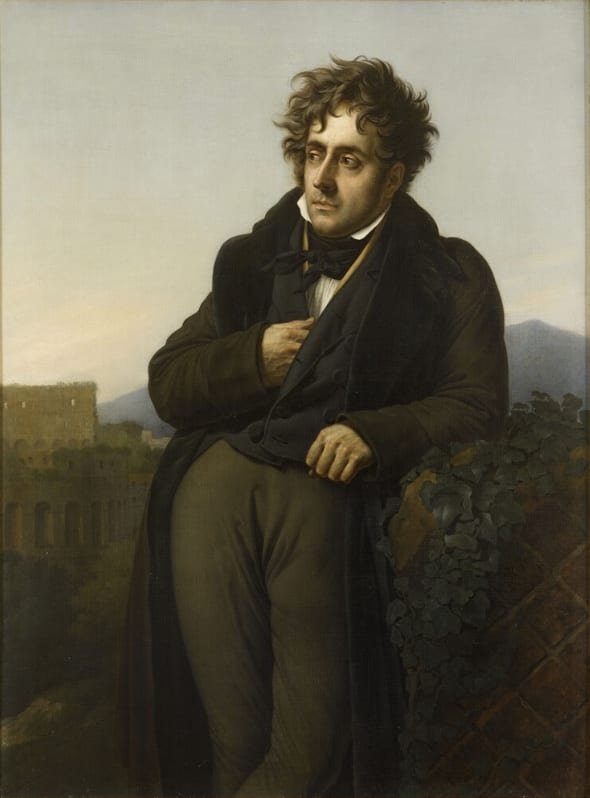Portrait en pied d'un homme appuyé à un muret, ruines d'un amphithéâtre à l'arrière-plan