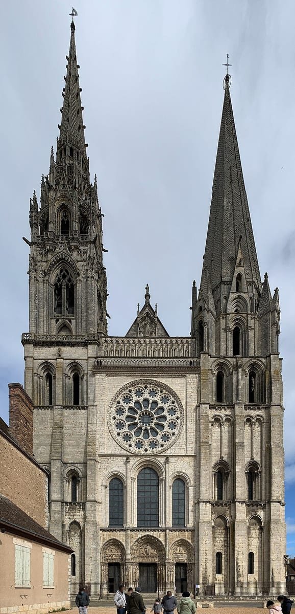 Façade d'une cathédrale gothique avec une rosace et deux flèches de styles différents