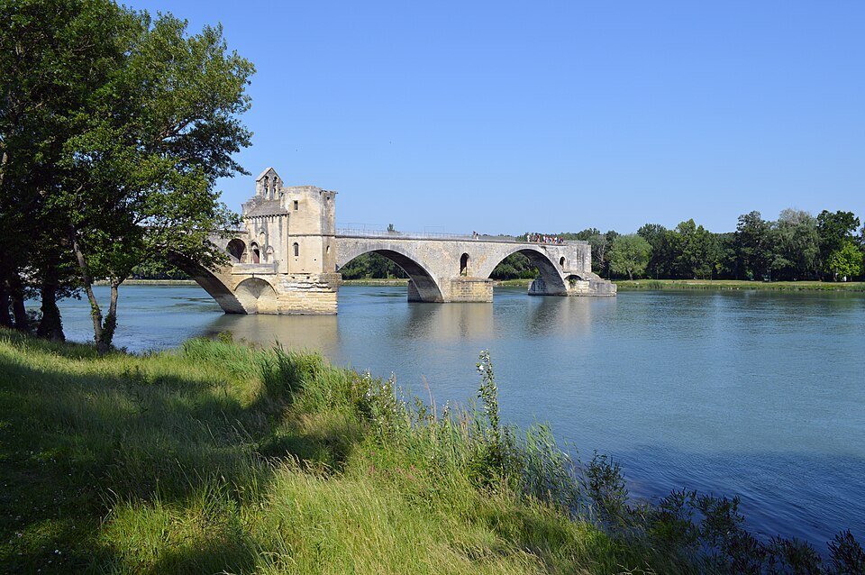 Vieux pont de pierre à quelques arches, avec une petite chapelle, interrompu au milieu d'un large fleuve