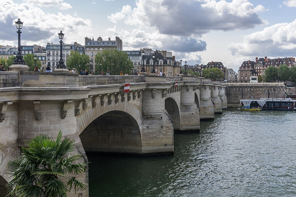 Pont de pierre à plusieurs arches enjambant un fleuve, ciel nuageux