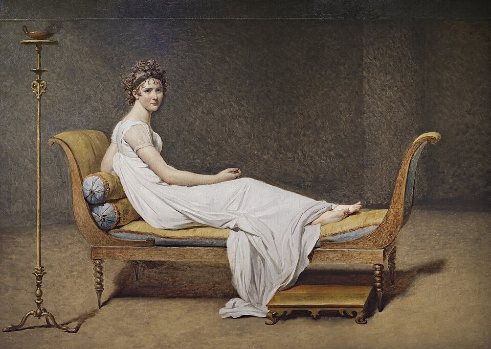 Portrait d'une jeune femme en robe blanche à l'antique, allongée sur un sofa, pieds nus